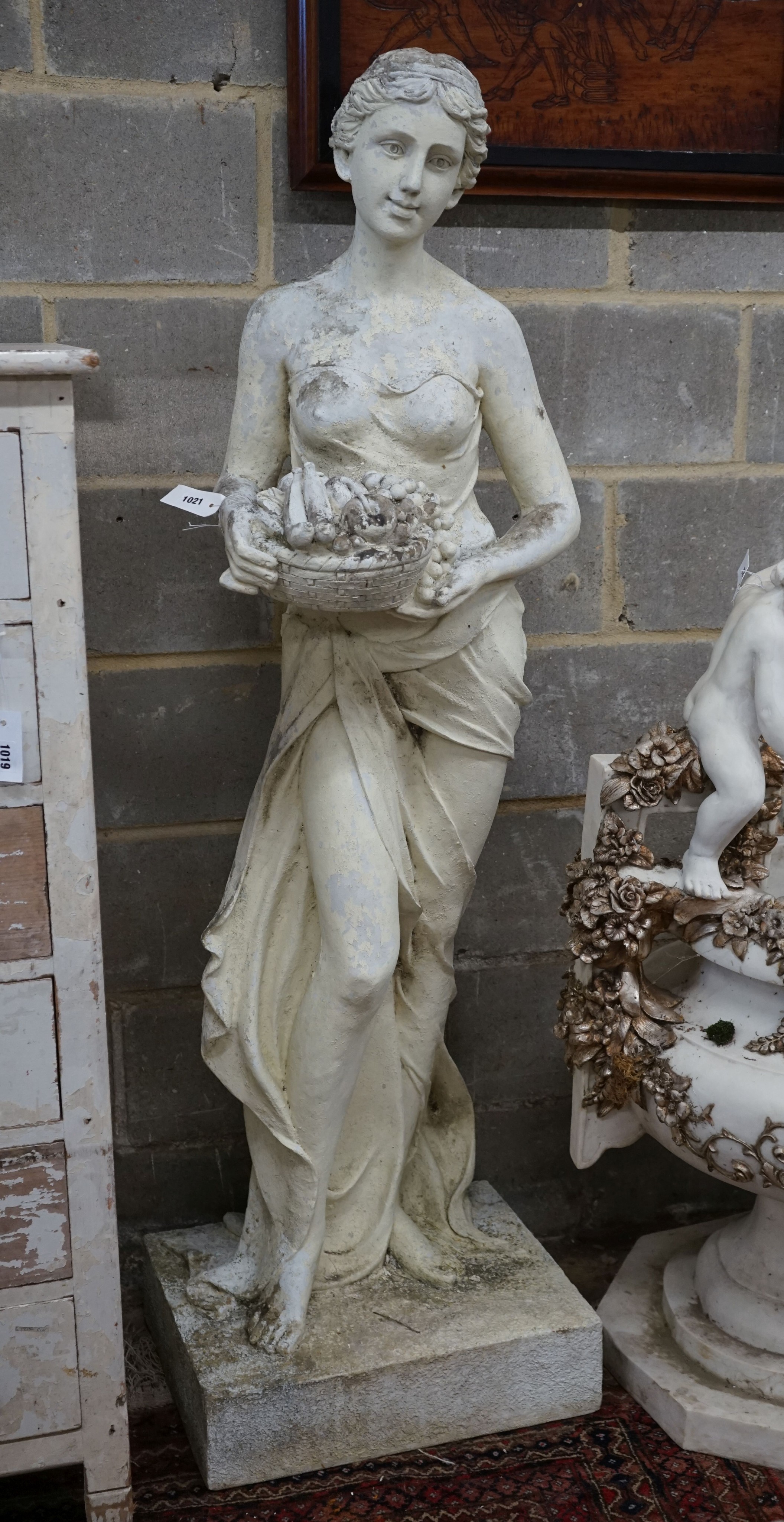 A large painted composition faux marble garden ornament, modelled as a girl with basket of fruit, height 160cm